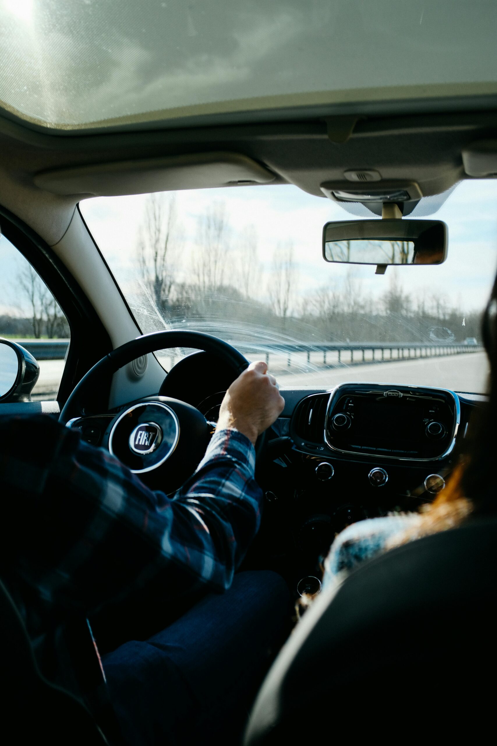 Interior view of a car on a highway, capturing the driver and passenger enjoying the ride.